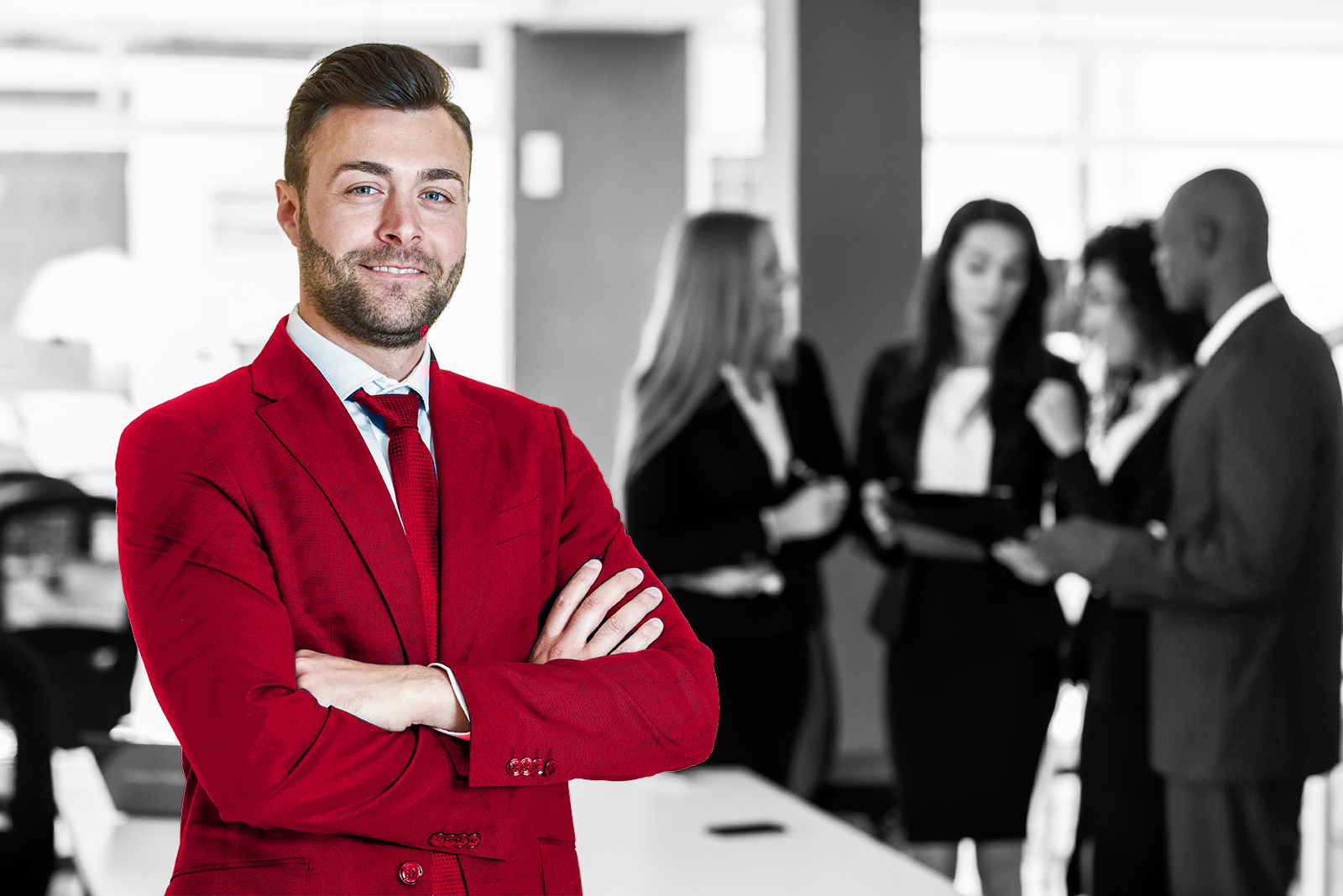 Caucasian businessman leader looking at camera in modern office with multi-ethnic businesspeople working at the background. Teamwork concept. Young man with beard wearing blue suit.